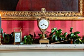 MARBURY HALL, SHROPSHIRE: DESIGNER SOFIE PATON-SMITH - THE LIBRARY, RED, CHRISTMAS DECORATIONS ON MANTELPIECE, CLOCK