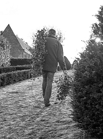 WARDINGTON_MANOR_OXFORDSHIRE_BLACK_AND_WHITE_PHOTO_OF_FLORIST_SHANE_CONNOLLY_CARRYING_IVY_CUT_FROM_T