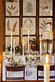 WARDINGTON MANOR, OXFORDSHIRE: FLORIST SHANE CONNOLLY - DINING ROOM: REFLECTION IN MIRROR - CANDLES, VASES, CONTAINERS WITH CHRISTMAS ROSE, HELLEBORES, INDOOR, FLOWERS