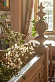 WARDINGTON MANOR, OXFORDSHIRE: FLORIST SHANE CONNOLLY - LIVING ROOM, HALLWAY - BALCONY WITH NATURAL CHRISTMAS DECORATIONS - HONESTY AND HOLLY