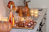 MERRYWOOD, JACKY HOBBS HOUSE, LONDON: WHITE KITCHEN, CHRISTMAS: ORANGE PUMPKINS, CANDLES, TRAY, BRONZE AND GOLD DECORATIONS, CHAMPAGNE