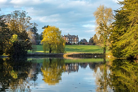 THENFORD_GARDENS__ARBORETUM_NORTHAMPTONSHIRE_VIEW_OF_THE_HOUSE_FROM_THE_LAKE_IN_SPRING