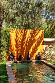 TAROUDANT, MOROCCO: DESIGNERS ARNAUD MAURIERES AND ERIC OSSART: DAR AL HOSSOUN - CANAL, POOL, WATER, ORANGE WALL, OLIVE TREES, SWIMMING POOL