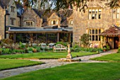 GRAVETYE MANOR SUSSEX: SPRING, APRIL, COUNTRY, GARDEN, LUTYENS BENCH, SEAT ON LAWN, PATHS AND STONE SUNDIAL, RESTAURANT TO THE LEFT
