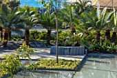 RADICEPURA GARDEN FESTIVAL, SICILY, ITALY: HOME GROUND BY ANTONIO PERAZZI. WATER GARDEN WITH TREES, WATER FEATURE, PALM TREES, SEATING, BENCHES MADE FROM RECYCLED STONE SLABS