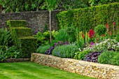 WINSON MANOR, GLOUCESTERSHIRE: BORDERS IN RAISED STONE WALL BED, LUPINS, HEUCHERAS, SUMMER, YEW HEDGING, HEDGES
