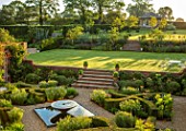 MANOR FARM, CHESHIRE: VIEW ONTO FORMAL HERB GARDEN - STEPS, GRAVEL, WATER FEATURE, BOX HEDGES, HEDGING, AMSONIA SALICIFOLIA, LAWN, SUMMERHOUSE