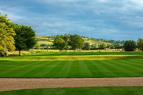 ADMINGTON_HALL_WARWICKSHIRE_GRAVEL_DRIVE_AT_FRONT_OF_HALL_SUMMER_VIEW_OF_LANDSCAPE_BEYOND_LAWN_BORRO