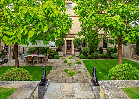 WINSON_MANOR_GLOUCESTERSHIRE_STEPS_CATALPAS_TERRACE_PATIO_STATUES_TABLE_CHAIRS_SUMMER_ENGLISH_COUNTR