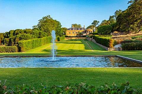 THE_NEWT_IN_SOMERSET_VIEW_TO_HOUSE_ACROSS_BATHING_POND_FOUNTAIN_LONG_GRASS_WALK_JULY_ENGLISH_COUNTRY