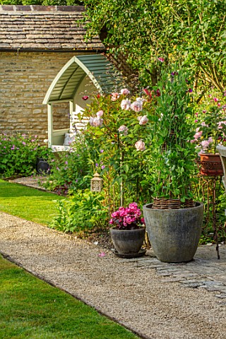 ADAMS_POOL_GLOUCESTERSHIRE_PATH_LAWN_SWEET_PEAS_IN_CONTAINER_TABLE_AND_CHAIRS_COVERED_SEAT_BENCH