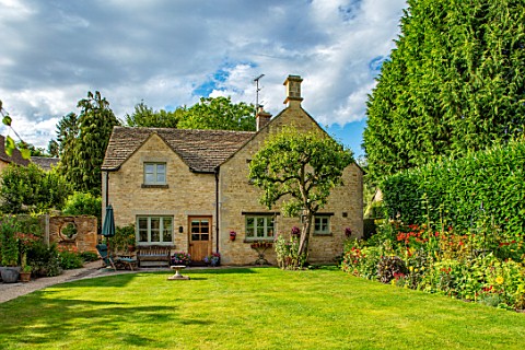ADAMS_POOL_GLOUCESTERSHIRE_LAWN_AND_HOUSE_WITH_HOT_BORDER_ON_RIGHT_COTTAGE_GARDEN_COTSWOLDS