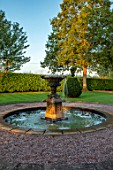 MITTON MANOR, STAFFORDSHIRE: FOUNTAIN AND CLIPPED YEW TOPIARY IN THE FRONT GARDEN. FOUNTAIN, POOL, FORMAL, LAWN, SUNRISE, COUNTRY, GARDEN, ENGLISH, LAWN, WATER