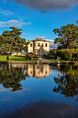 THORP PERROW ARBORETUM, YORKSHIRE: HOUSE ACROSS THE LAKE IN AUTUMN. TREES, LAKES, WATER, EVENING LIGHT, REFLECTIONS, REFLECTED