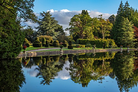 THORP_PERROW_ARBORETUM_YORKSHIRE_CLIPPED_TOPIARY_YEW_HOUSE_ACROSS_THE_LAKE_IN_AUTUMN_TREES_LAKES_WAT
