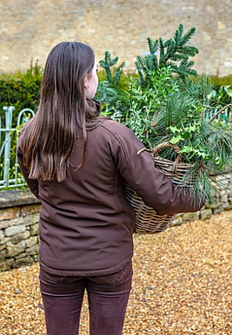 DAYLESFORD_ORGANIC_GLOUCESTERSHIRE_GIRL_HOLDING_FORAGED_MATERIALS_FROM_ESTATE_CHRISTMAS_DECORATIONS_