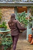 DAYLESFORD ORGANIC, GLOUCESTERSHIRE: GIRL HOLDING FORAGED MATERIALS FROM ESTATE, CHRISTMAS, DECORATIONS, GRAVEL