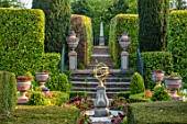 THE LASKETT GARDENS, HEREFORDSHIRE. DESIGNER ROY STRONG - THE SILVER JUBILEE GARDEN, SUNDIAL, BRICK PATH, URNS, CONTAINERS, TULIPS, BOX HEDGING, HEDGES, SPRING, APRIL