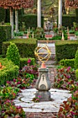 THE LASKETT GARDENS, HEREFORDSHIRE. DESIGNER ROY STRONG - THE SILVER JUBILEE GARDEN, SUNDIAL, BRICK PATH, BOX HEDGING, HEDGES, BERGENIA, SPRING, APRIL