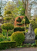 THE LASKETT GARDENS, HEREFORDSHIRE. DESIGNER ROY STRONG - THE SERPENTINE WALK - STATUE OF BRITANNIA, CLIPPED, TOPIARY, BOX, HOLLY, ILEX, BUXUS, SPRING, APRIL
