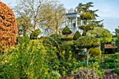 THE LASKETT GARDENS, HEREFORDSHIRE. DESIGNER ROY STRONG - THE SERPENTINE WALK, CLIPPED TOPIARY HOLLIES, YEW, BELVEDERE, BUILDINGS, SPRING, APRIL