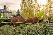 THE LASKETT GARDENS, HEREFORDSHIRE. DESIGNER ROY STRONG - VIEW ACROSS GARDEN TO THE HOUSE FROM THE BELVEDERE, EARLY MORNING, APRIL, SPRING