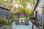 LITTLE ORCHARDS, SURREY, DESIGNER NIC HOWARD: SPRING, APRIL, COURTYARD, TABLE, CHAIRS, PATHS, LAWN, PINK WALL, SUNSET, EVENING LIGHT
