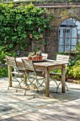 LITTLE ORCHARDS, SURREY, DESIGNER NIC HOWARD: COURTYARD, PATIO, WOODEN TABLE, CHAIRS, PAVING, MIRROR, SPRING, APRIL