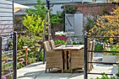 LITTLE ORCHARDS, SURREY, DESIGNER NIC HOWARD: SPRING, APRIL, COURTYARD, TABLE, CHAIRS, CONTAINER WITH TULIPA RONALDO, PATHS, LAWN, SUNSET, EVENING LIGHT, GATES
