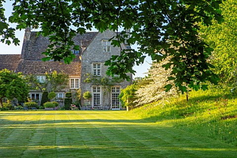 VILLAGE_FARM_HOUSE_GLOUCESTERSHIRE_HOUSE_MEADOW_LAWN_SPRING_MAY_MALUS_TRANSITORIA_UNDERPLANTED_WITH_