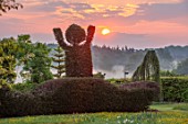 THE MANOR HOUSE, STEVINGTON, BEDFORDSHIRE: BOY WITH ARMS ALOFT CLIPPED TOPIARY YEW HEDGING, HEDGES, SUNRISE, COUNTRY, GARDEN, ENGLISH, SPRING, MAY
