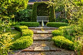 COTTAGE ROW, DORSET: GRAVEL PATH TO YEW ARCH WITH WOODEN SEAT, BENCH, BOX HEDGING, WATER FEATURE, GREEN, FOCAL POINT, ORNAMENT