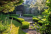 COTTAGE ROW, DORSET: GRAVEL PATH TO YEW ARCH WITH WOODEN SEAT, BENCH, BOX HEDGING, WATER FEATURE, GREEN, FOCAL POINT, ORNAMENT