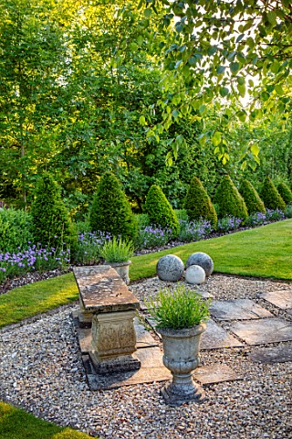 ORDNANCE_HOUSE_WILTSHIRE_GRAVEL_STONE_SEAT_BENCH_LAWN_CLIPPED_TOPIARY_CONES_MAY_SPRING_FRONT_GARDEN