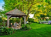 ORDNANCE HOUSE, WILTSHIRE: MAY, SPRING, THE ORCHARD ROOM, OUTDOOR SEATING AREA, BUILDING, HUT, PERGOLA, TABLE AND CHAIRS