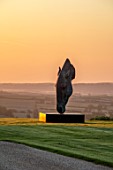 NEVILL HOLT, LEICESTERSHIRE: DAWN, SUNRISE, SCULPTURE OF HORSE HEAD BY NIC FIDDIAN GREEN, LAWN