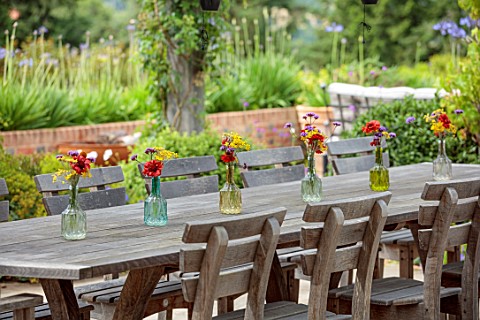 ALDERWOOD_HOUSE_KENT_TERRACE_PATIO_WOODEN_TABLE_CHAIRS_GLASS_JARS_ON_TABLE_WITH_GALLARDIA_BURGUNDY_V