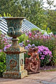 LARCH COTTAGE NURSERIES, CUMBRIA: URNS, CONTAINERS, STATUE, BORDER OF PHLOX, BORDERS, ORNAMENTS, FORMAL, PINK FLOWERS, SUMMER, GREENHOUSE