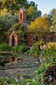 LARCH COTTAGE NURSERIES, CUMBRIA: POOL, POND, WATER, WATERLILIES, CHAPEL BUILT IN 2014 BY PETER STOTT, STORMY WEATHER, EVENING LIGHT, GARDEN, BUILDING, HOSTAS, WILLOWS, REFLECTIONS