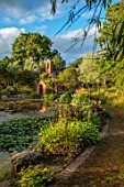 LARCH COTTAGE NURSERIES, CUMBRIA: POOL, POND, WATER, WATERLILIES, CHAPEL BUILT IN 2014 BY PETER STOTT, STORMY WEATHER, EVENING LIGHT, GARDEN, BUILDING, HOSTAS, WILLOWS, REFLECTIONS