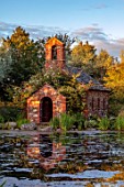 LARCH COTTAGE NURSERIES, CUMBRIA: POOL, POND, WATER, WATERLILIES, CHAPEL BUILT IN 2014 BY PETER STOTT, STORMY WEATHER, EVENING LIGHT, GARDEN, BUILDING, REFLECTIONS, REFLECTED