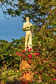 LARCH COTTAGE NURSERIES, CUMBRIA: STATUE AND RED ROSE ON WALL IN THE NURSERY IN SUMMER, JULY