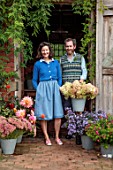 THE FLOWER GARDEN AT STOKESAY COURT: BARNEY AND MARTIN BESIDE THE POTTING SHED WITH DAHLIAS, ASTERS AND HYDRANGEAS IN CONTAINERS
