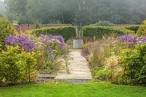 WILDEGOOSE_NURSERY_SHROPSHIRE_DOUBLE_BORDERS_IN_SEPTEMBER_PATHS_METAL_CONTAINER_WITH_SCULPTURE_ASTER