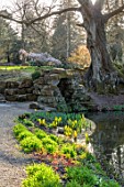 HEVER CASTLE, KENT: POOL, GROTTO, POND, WATER, ROCKS, SKUNK CABBAGE, LYSICHITON AMERICANUS, TREE, MARCH