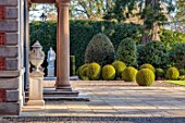 MORTON HALL, WORCESTERSHIRE: FRONT TERRACE OF HALL, SPRING, APRIL, STONE URNS, STATUE, TERRACE, CLIPPED TOPIARY BOX BALLS
