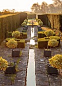 LOWER BOWDEN MANOR, BERKSHIRE: SPRING, APRIL, SUNRISE, MORNING, THE RILL, WATER, CANAL, VERSAILLES CONTAINERS, STANDARD EUONYMUS BRAVO