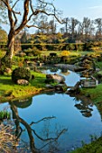 LOWER BOWDEN MANOR, BERKSHIRE: SPRING, APRIL, POND, POOL, YEW BALLS, CLOUD PRUNED TREE IN WOODEN BOX, CONTAINER, BOULDERS, REFLECTIONS, REFLECTED